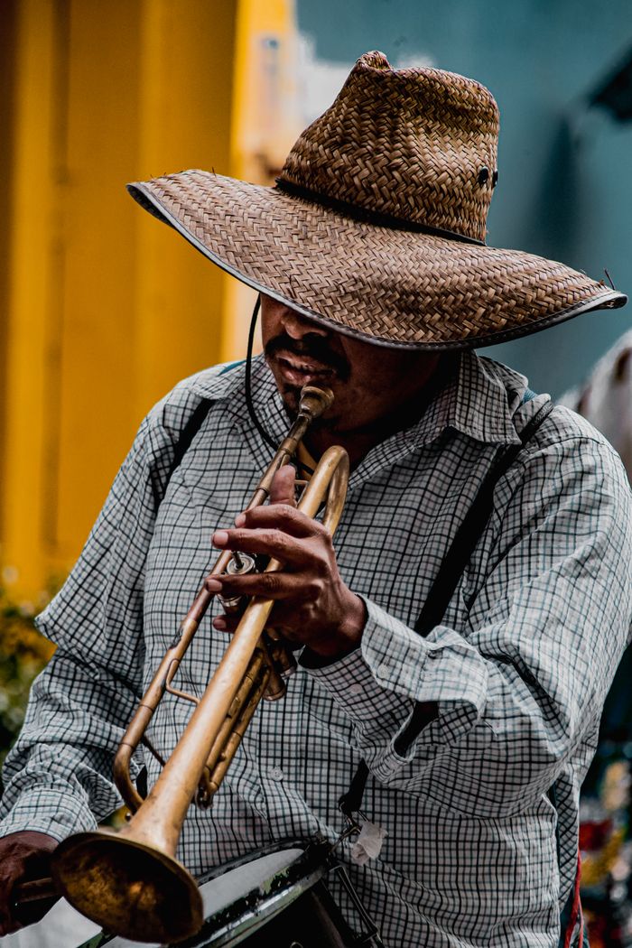 A street musician in Puebla, Mexico, wearing a straw hat and playing trumpet outdoors.