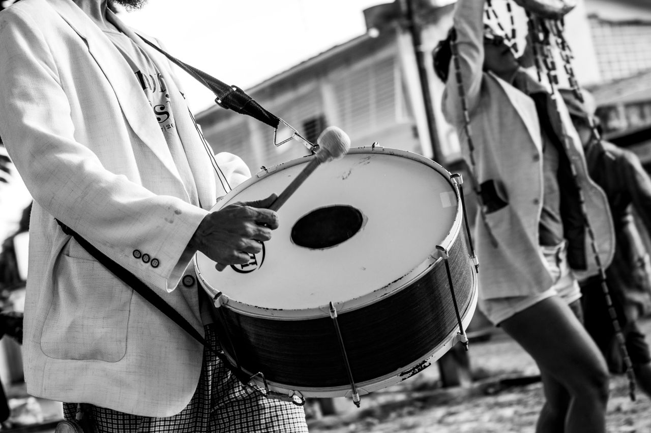 Black and white photo of a street musician playing a drum in Olinda, Brazil.