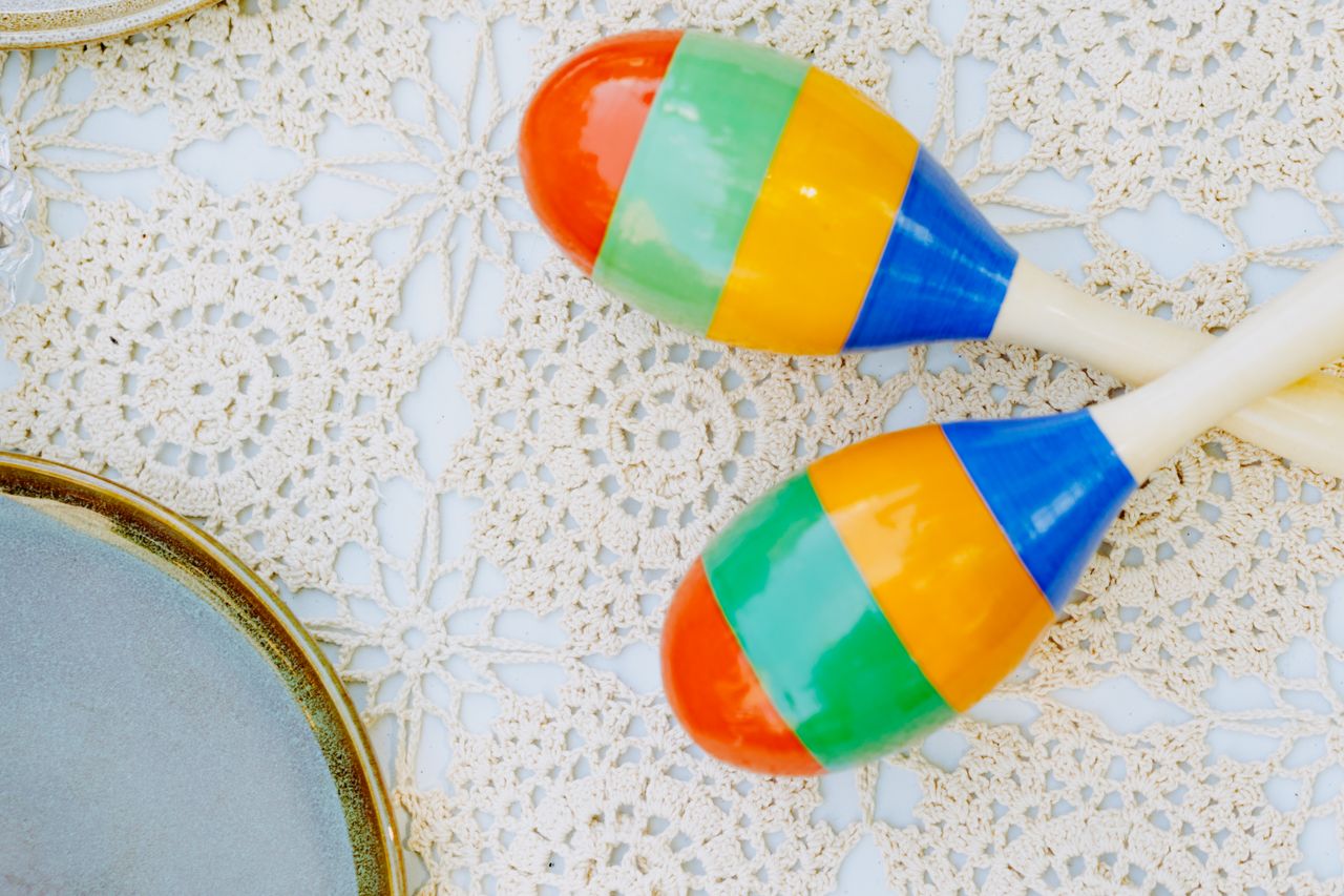 Bright maracas placed on crochet lace in a flat lay composition, perfect for festive or cultural concepts.